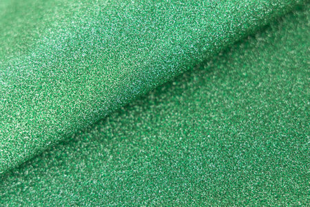 Green shiny glitter wave paper texture. Glow luxurious fabric. Light green color st Patric background. Empty spaceの写真素材