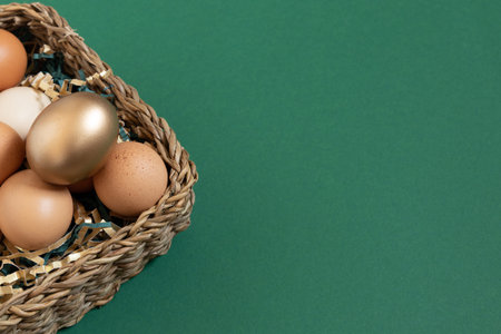 Easter eggs natural and gold in basket with paper filler . Branch of willow catkins. Light pastel orange background with copy space.の写真素材