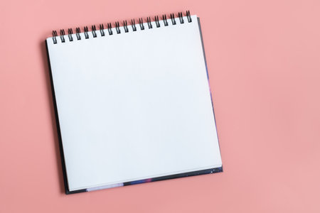 Mock up of empty spiral sketchbook with white paper on pastel pink background. Top view of open notebook with clean sheet. Template for message. Copy spaceの写真素材
