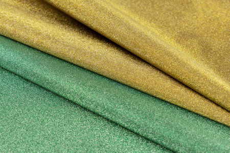Golden and green wave shiny glitter paper texture. Shining luxurious fabric. Glimmering light green golden color, christmas backgroundの写真素材