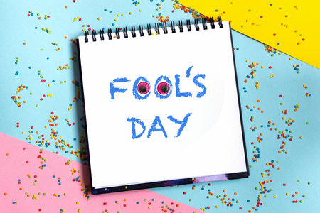 Text word Fool's day on scketchbook with funny eyes and confetti at background. 1 april message handwritting on sheet of paper. International humor dayの写真素材