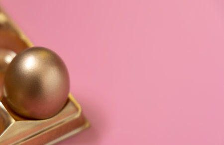 Happy Easter holiday. Golden easter egg in golden box on pastel pink backgroundの写真素材
