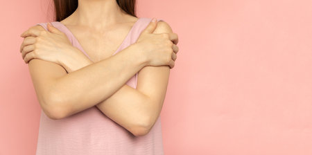 Embrace equity. Woman hug yourself dressed pastel pink dress on pink background. International women's day concept. Pastel colors, copy spaceの写真素材