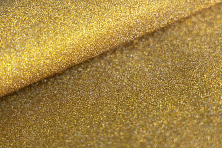 Golden wave shiny glitter paper texture. Shining luxurious fabric. Glimmering golden color, christmas background.の写真素材