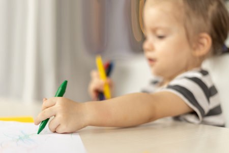 Adorable caucasian baby girl drawing greeting card for mothers day. Image with selective focus on handの写真素材