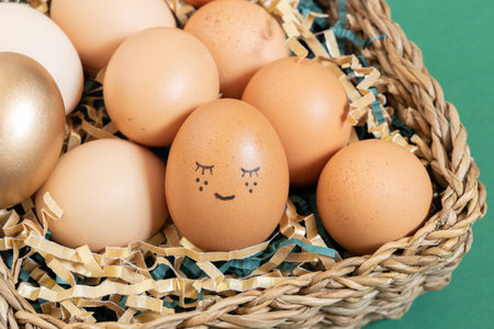 Close up of easter eggs with funny face natural and gold in basket with paper filler.の写真素材
