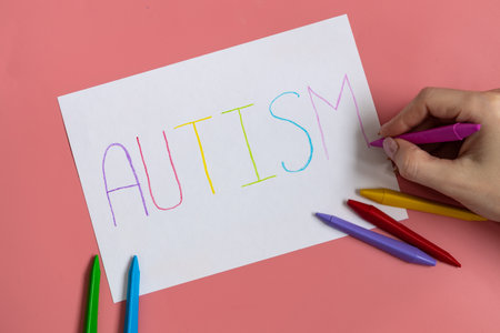 Text word autism on paper sheet written by colorful letter, on blue background.の写真素材