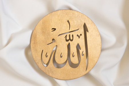 Allah bismillah names close up. Golden wooden calligraphy of islamic god. on white textile, top viewの写真素材
