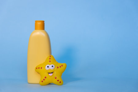 Yellow layout of a childrens cosmetic product with a place for a logo and funny toy on a blue background. Baby shampoo, shower gel or body lotion. Space for textの写真素材