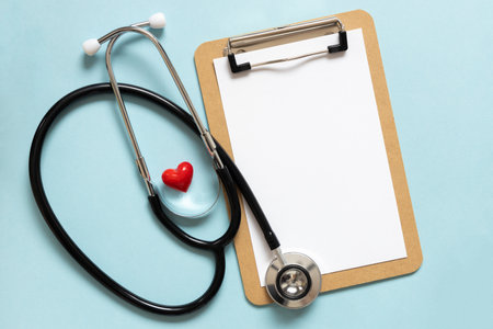 Cardiologist day. Stethoscope, flowers and heart shape, space for text on blue backgroundの写真素材