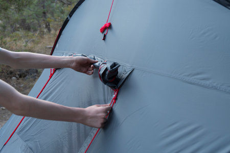 Close up of hands pitching gray tent on camping trip with camping equipmentの写真素材
