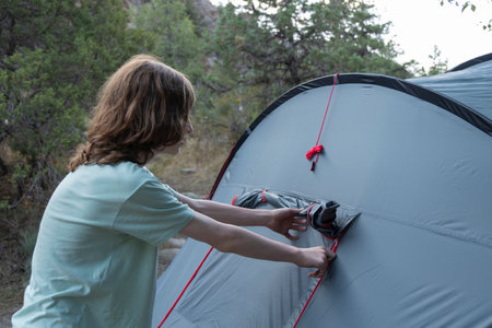 Close up pitching grey tent on camping trip with camping equipment.の写真素材