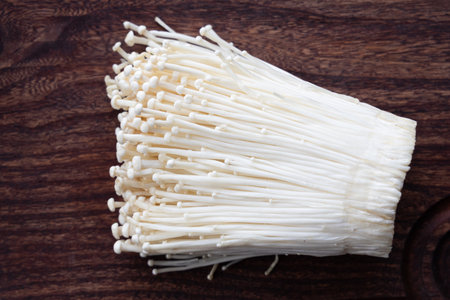 Cluster of enoki mushrooms on dark wood.の写真素材