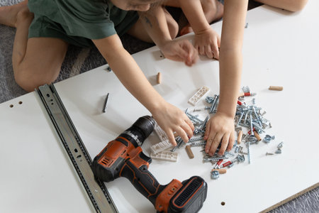 Kids participate in assembling a wardrobe, teamwork and DIY concept, real family life and learning practical skillsの写真素材