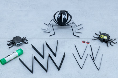 Step 2 of 5 making paper spider for Halloween. Cutting black paper into thin strips to form spider legs for handmade Halloween decorationの写真素材