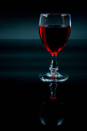 A wineglass with red wine on a dark backgroundの写真素材