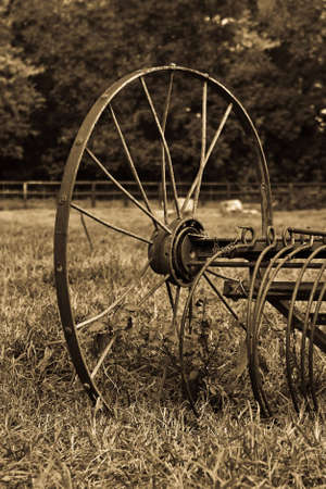 Rusty old plough standing in a field of grass in sepiaの写真素材