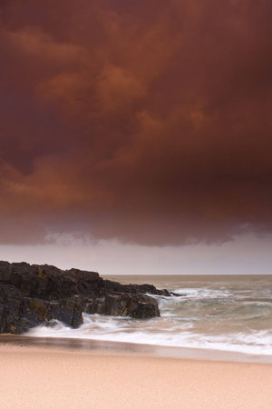 Storm brewing over rocky shore and sandy beach of Winkelspruit near Durban