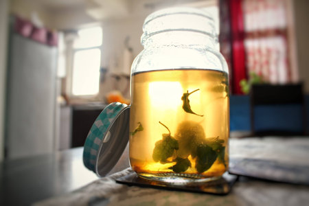 Closeup of mason jar with herbal tea with basil leaves kept on a table and lid on its sideの写真素材