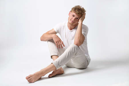 Handsome emotional man with a smile posing in a studio on light backgroundの写真素材