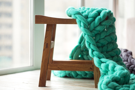Green knitted merino wool blanket on wooden chairの写真素材