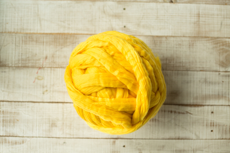 Yellow merino wool ball on wooden backgroundの写真素材