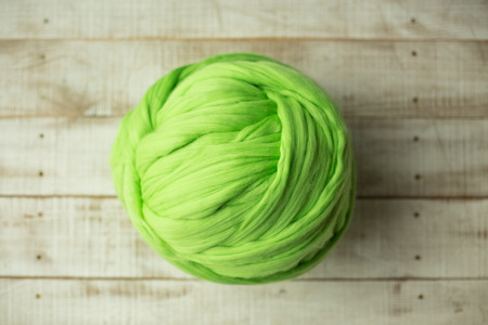Green merino wool ball on wooden backgroundの写真素材
