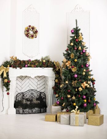 Beautiful holiday decorated room with fireplace and Christmas tree with presents under itの写真素材