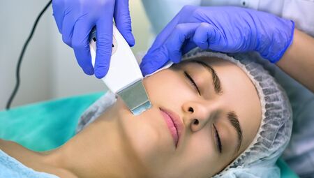 Cosmetologist doing a procedures, ultrasonic skin cleaning, young woman at cosmetologist.の写真素材