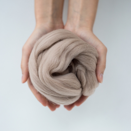 Close-up of brown merino wool ball in hands.の写真素材