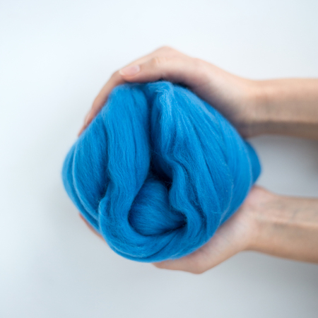 Close-up of blue merino wool ball in hands.の写真素材