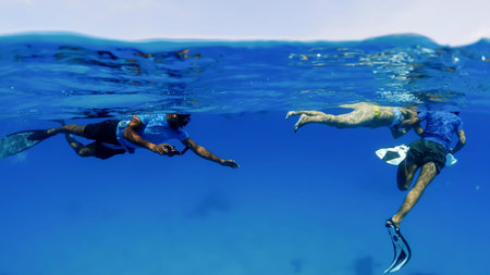 Group of people in the open ocean snorkeling reef excursion, Underwater split shot photosのeditorial素材