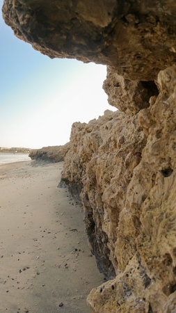 Close-up over a cliff on the coastline of the sea and sandy beach in the afternoonの写真素材