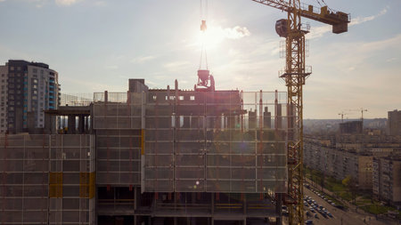 View of the roof of a high-rise building under construction with workers and the background of the...