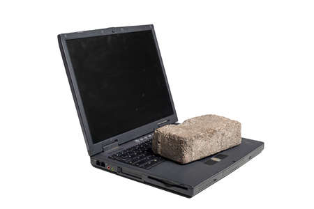 Old broken laptop with brick on us on white backgroundの写真素材