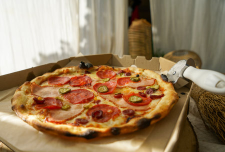 Juicy, fragrant delicious pizza on the table on a sunny dayの写真素材