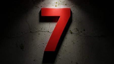 A red number seven on a dark concrete surface, illuminated by a spotlight.の素材
