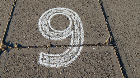 Number nine drawn with white chalk on a concrete pavement surfaceの素材