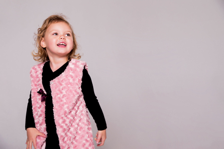 happy fashionable little girl in a black suit and a pink waistcoatの写真素材