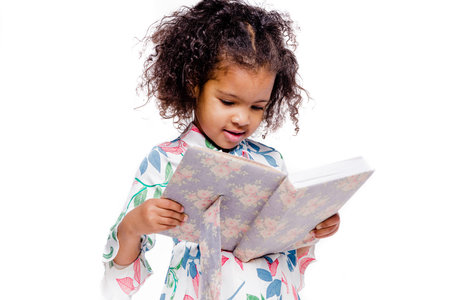 Little pretty fashionable african american girl in white floral dress looking at notebook