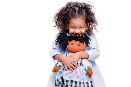 Portrait of a cute little african american girl hugging doll, isolated on white backgroundの写真素材