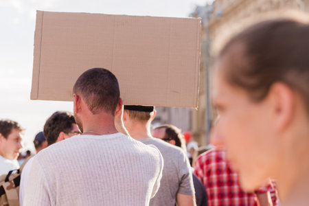 Peaceful demonstration in the city. Man with a poster stands with his back to the camera. Horizontal...