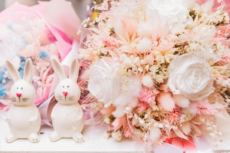 A bouquet of dried flowers as a decor and two porcelain hares next to each other. Horizontal photo