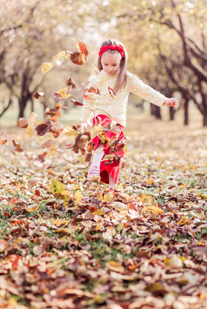 A little girl in a long red skirt, a warm yellow jacket and a red bandage on her head is buzzing...