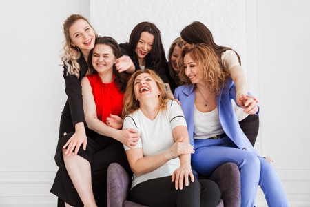 Seven diverse colleagues, co-workers stand ans seat together in office, hug each other. Horizontal...