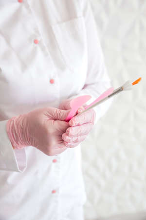 Professional beautician with brushes in hands. Woman beautician posing against white wall background. Horizontal photoの写真素材