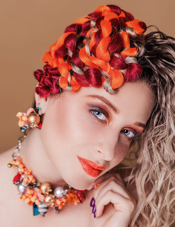 Beautiful girl with autumn hairstyle and makeup posing on a beige background. Vertical photo