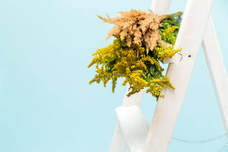 Bouquet of yellow wildflowers on a white staircase on a yellow background. Horizontal photoの写真素材