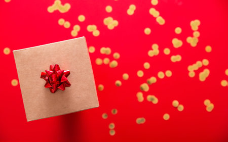 Gift wrapped on a red background and golden confetti
