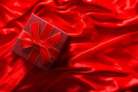 Gift in red packaging on a red silk background